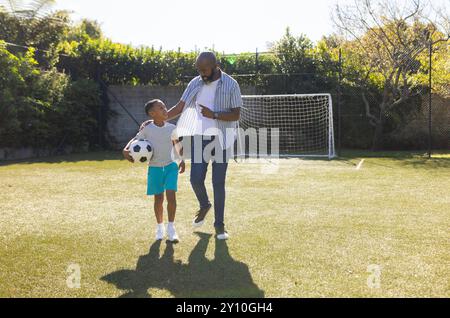 Fußball spielen, Großvater und Enkel gehen mit Ball auf dem Spielfeld, arbeiten im Freien, Kopierraum Stockfoto