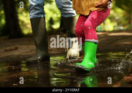 Mutter und Tochter tragen Gummistiefel, gehen draußen in der Pfütze, Nahaufnahme Stockfoto