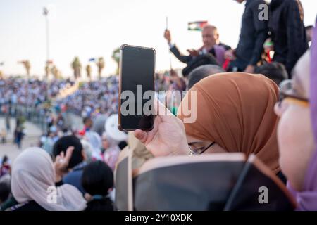 Weibliche Hand, die ihr Handy auf Stadionstühlen hält, nimmt während des Sports oder bei Veranstaltungen Videos über ihr Smartphone auf Stockfoto