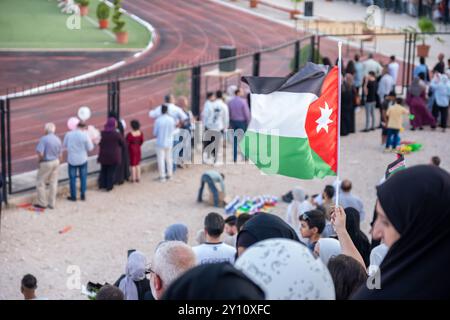 Ein Fan schwingt stolz die jordanische Flagge und jubelt mit Hoffnung auf einen jordanischen Sieg bei einem Sportereignis Stockfoto