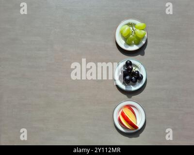 Frisches Obst auf einem weißen Teller, eine vitaminreiche Ernährung, gesunde frische helle und dunkle Trauben und geschnittene rote Apfel Stockfoto