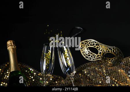 Schöne Karnevalsmasken, Champagner, Gläser und Stoff mit goldenen Pailletten auf schwarzem Hintergrund, flach gelegt Stockfoto