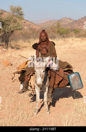 Porträt einer jungen verheirateten Himba-Frau mit einem kleinen Kind auf einem Esel, Kaokoveld, Nord-Namibia, Namibia Stockfoto