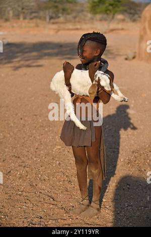 Limba-Mädchen, das eine junge Ziege im Arm hält, Kunene, Kaokoveld, Namibia Stockfoto