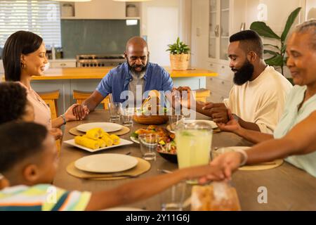Hände halten, generationenübergreifende Familie betet vor dem Essen am Esstisch zu Hause Stockfoto