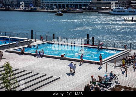 Mittsommerabend in der Stadt: Menschen schwimmen und sonnen auf der schwimmenden Terrasse des Allas SE Pool in Helsinki, Finnland Stockfoto