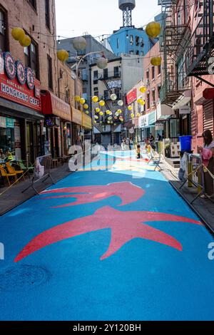 New York, NY, USA. September 2024. Die Künstlerin Colleen Kong-Savage leitet eine Mannschaft von Freiwilligen an einem Projekt für den New Yorker Chinatown Business Improvement District, um ein Wandbild auf der gesamten Doyers Street zu malen, einer 200 Fuß (61 m) langen Fußgängerzone mit Restaurants und kleinen Unternehmen. Quelle: Ed Lefkowicz/Alamy Live News Stockfoto