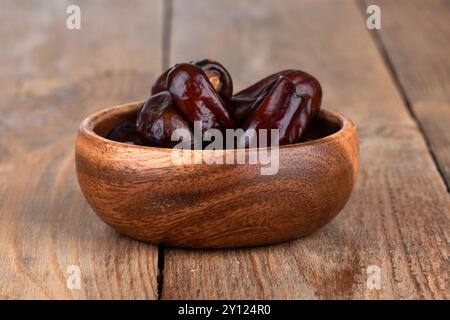 Holzschale mit trockenen Datteln auf einem Holztisch. Nahaufnahme. Stockfoto