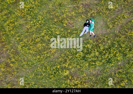 Blick auf zwei junge Frauen, die auf dem blühenden Wiesenrasenfeld liegen. Frühling im Freien Stockfoto