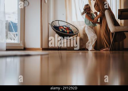 Fröhliche Mutter und Tochter tanzen zusammen im hellen Wohnzimmer Stockfoto