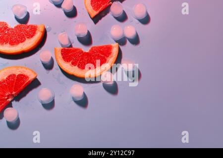 Grapefruitscheiben mit Eiswürfeln auf blauem Hintergrund Stockfoto