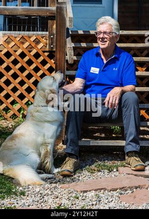 Erwachsener Mann sitzt auf einer Außentreppe mit platinfarbenem Golden Retriever Hund Stockfoto