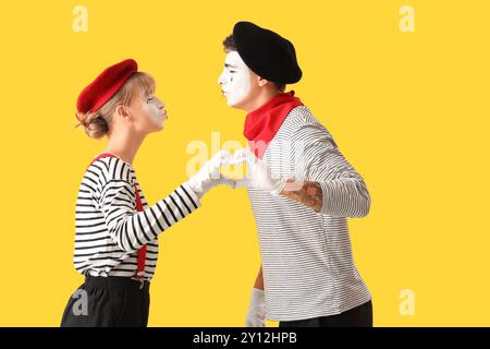 Ein paar Pantomimisten machen Herz mit ihren Händen auf gelbem Hintergrund Stockfoto