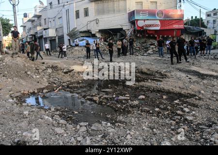 Jenin, Palästina. September 2024. Palästinenser gehen durch eine zerstörte Straße im Zentrum der Stadt Dschenin im nördlichen Westjordanland, nachdem sie von israelischen Truppen nach einem Angriff zerstört wurde, der ihren siebten Tag auf die Stadt eintrat. (Foto: Nasser Ishtayeh/SOPA Images/SIPA USA) Credit: SIPA USA/Alamy Live News Stockfoto