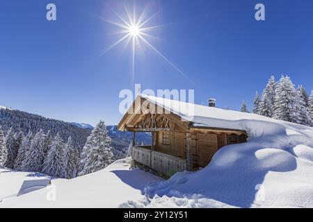 Almhütte im Winter mit Sonne, Schnee, Sonnenstrahlen, Hoernle-Alm, Ammergauer Alpen, Oberbayern, Bayern, Deutschland, Europa Stockfoto