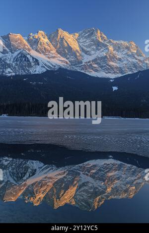 Steile Berge spiegeln sich im Winter im Bergsee, Eis, Abendlicht, Eibsee, Zugspitze, Bayern, Deutschland, Europa Stockfoto