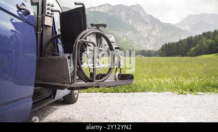 Foto des Spezialfahrzeugs für den Elektroaufzug in Schwarz für Menschen mit Behinderungen. Leerer Rollstuhl auf einer Rampe mit Natur und Bergen im Rücken Stockfoto