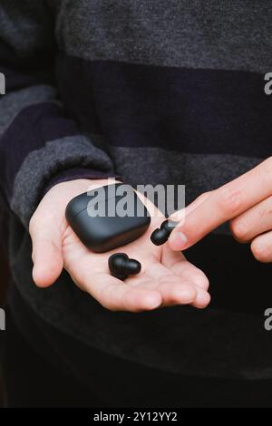 Mann mit schwarzen schnurlosen Ohrstöpseln und Einer Tasche. Moderner Lifestyle Stockfoto