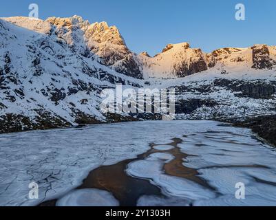 Aus der Vogelperspektive auf den eisigen See vor den steilen Bergen, Winter, Sonnenaufgang, Storvatnet, Flakstadoya, Lofoten, Norwegen, Europa Stockfoto