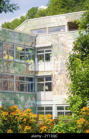 Modernes Gebäude mit Wandkunst und vielen Fenstern, umgeben von Pflanzen im Sommer, Nagold, Schwarzwald, Deutschland, Europa Stockfoto