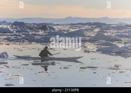 Inuit paddelt ein Kajak zwischen Eisbergen, Mann, Sonne, Sommer, Ilulissat, Ilulissat Icefjord, Disko Bay, Westgrönland, Grönland, Nordamerika Stockfoto