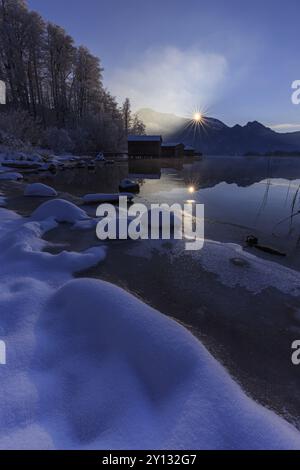 Abendstimmung am Bergsee vor Bergen, Bootshütten, Ufer, Winter, Schnee, Reflexion, Sonnenstrahlen, Hintergrundbeleuchtung, Kochelsee, Vorgebirge, B Stockfoto