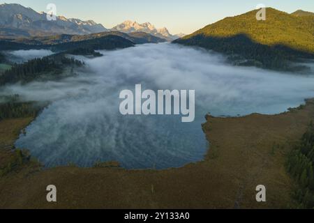 Aus der Vogelperspektive auf einen Bergsee vor den Bergen, Sonnenaufgang, Nebel, Herbst, Barmsee, Blick auf Zugspitze und Wetterstein, Oberbayern, Bavar Stockfoto