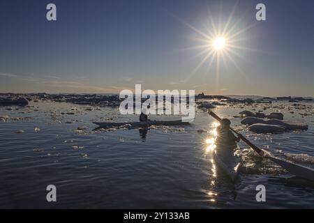 Inuit Kinder paddeln Kajaks zwischen Eisbergen, sonnig, Sommer, Ilulissat, Ilulissat Eisefjord, Disko Bay, Westgrönland, Grönland, Nordamerika Stockfoto