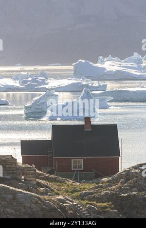 Typisches grönländisches Haus vor Eisbergen am Meer, Sommer, sonnig, Uummannaq, Westgrönland, Grönland, Nordamerika Stockfoto