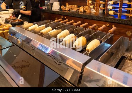 Der Schornsteinkuchen (Trdelnik) wird in einem Prager Geschäft um ein heißes Eisenrohr über einer heißen Kohle gebacken Stockfoto