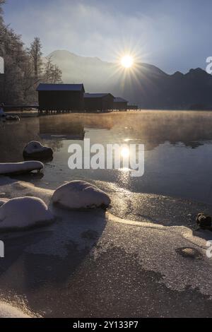 Abendstimmung am Bergsee vor Bergen, Bootshütten, Ufer, Winter, Schnee, Reflexion, Sonnenstrahlen, Hintergrundbeleuchtung, Kochelsee, Vorgebirge, B Stockfoto