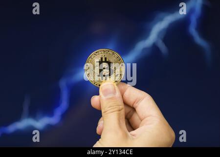 Mann hält Bitcoin gold Münze vor Blitzschlag netzwerk konzept Hintergrund Stockfoto