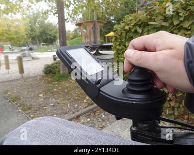 Mit Nahaufnahme eines behinderten Menschen Hand fahren elektrischen Rollstuhl Joystick Stockfoto