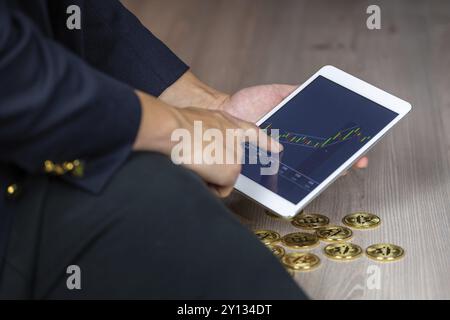 Geschäftsmann Handel auf Tablet online, bei cryptocurrency Bitcoin chart Suche mit Münzen rund um Stockfoto