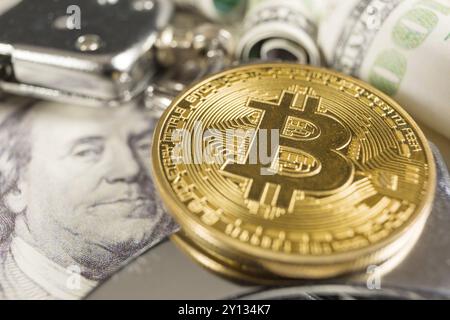 Goldene Bitcoins Kryptowährung mit Handschellen auf Dollarscheine. Digitales Verbrechen, Verhaftung oder Hacking-Konzept Stockfoto
