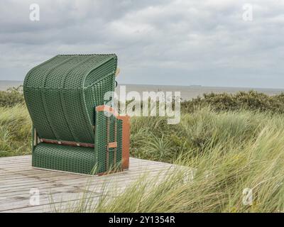 Eine grüne Liege auf einem Holzweg am Strand mit Blick aufs Meer, spiekeroog, ostfriesland, Nordsee, deutschland Stockfoto