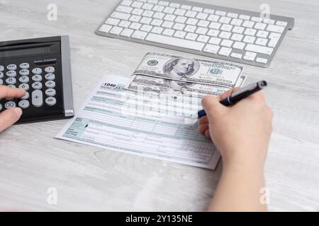 Sicht Foto von Frau Berechnung und füllen uns Steuerformular neben Computer Tastatur und Steuerformular 1040. 15. April 2019 Steuer Tag Stockfoto