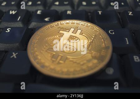 Goldene Bitcoin-Münze, die auf einer schwarzen Computertastatur liegt. Digital Money Konzept Stockfoto