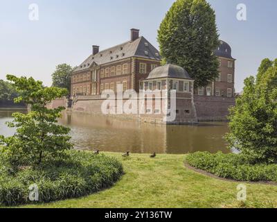 Ein historisches Backsteinschloss, umgeben von einem Graben mit üppigem Grün und Bäumen, die eine ruhige Atmosphäre schaffen, ahaus, münsterland, deutschland Stockfoto