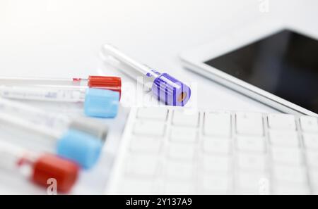 Nahaufnahme Foto von Medizin Flaschen für Proben neben Computer Tablet und Computer Tastatur im Krankenhaus oder Labor Stockfoto