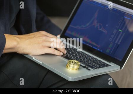 Geschäftsmann Handel auf Laptop online, bei cryptocurrency Bitcoin chart Suche mit Münzen rund um Stockfoto