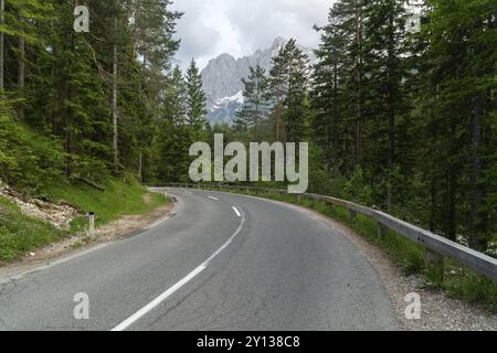 Weitwinkelfoto einer wunderschönen Straße für Autos im Wald mit Bergen im Rücken Stockfoto