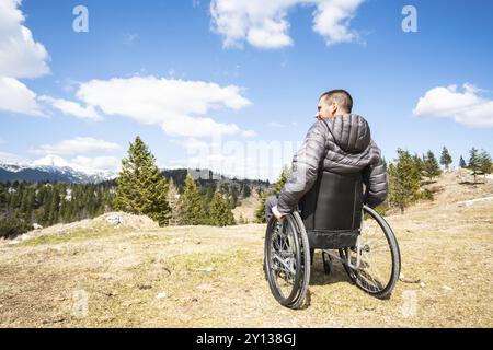 Junge behinderte Menschen im Rollstuhl in der freien Natur beobachten, Berge und Natur Stockfoto