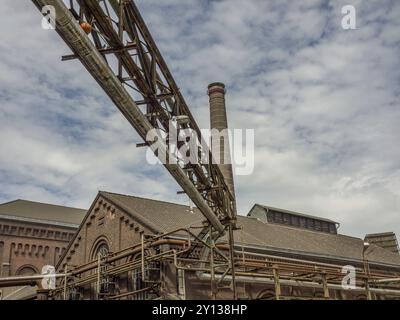 Historisches Fabrikgebäude mit Kamin und Stahlträgern unter bewölktem Himmel, Duisburg, Ruhrgebiet, Deutschland, Europa Stockfoto