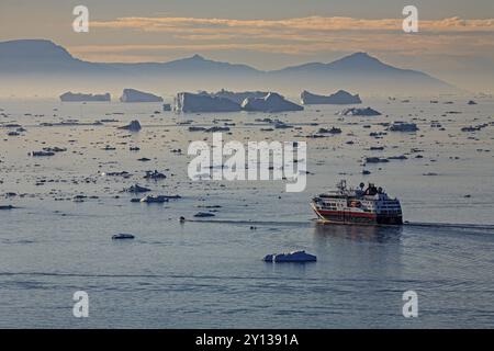 Hurtigruten-Schiff vor Eisbergen, Reflexion, Mitternachtssonne, Sommer, Ilulissat-Eisfjord, Disko Bay, Grönland, Nordamerika Stockfoto