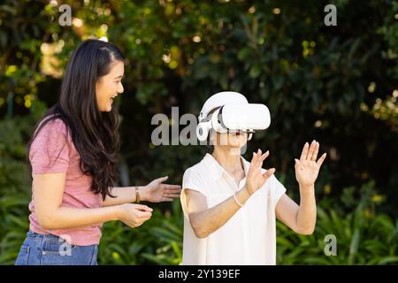Mit dem VR-Headset erkundet die asiatische Großmutter die virtuelle Realität mit ihrer Tochter im Freien Stockfoto