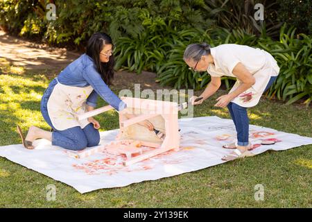 Stuhlmalerei im Freien, asiatische Großmutter und Gradntochter kooperieren am DIY-Projekt in Backyar Stockfoto