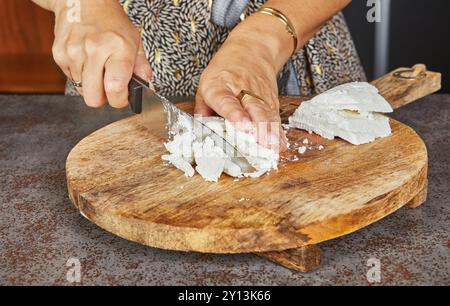 Nahaufnahmen von Händen, die Hartkäse auf hölzernen Schneidebrettern in der Küche schneiden. Stockfoto