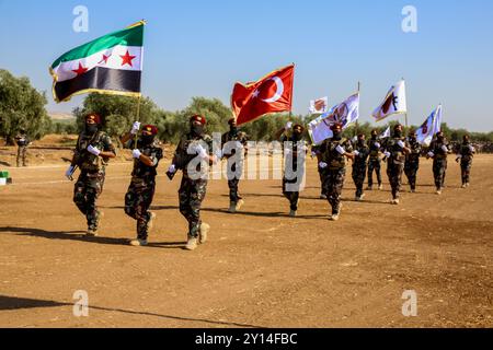 Aleppo, Syrien. Juli 2021. Im nordsyrischen Land Afrins findet eine militärische Zeremonie für den Abschluss von 2.500 Kämpfern der syrischen Nationalarmee (SNA) statt. Viele Kämpfer der SNA marschierten im Gebiet von Scheich Hadid in Afrin im Nordwesten Aleppos, während andere Motorräder und Pferde fuhren. Bilder von getöteten Kämpfern der syrischen Nationalarmee sowie die Flagge der syrischen Opposition und die türkische Flagge wurden bei der Veranstaltung gezeigt. Die SNA ist eine Koalition bewaffneter syrischer Gruppen, die gegen die Regierung von Präsident Bashar Al-Assad sind und mit der Türkei verbündet sind. Der Kopf der Syri Stockfoto