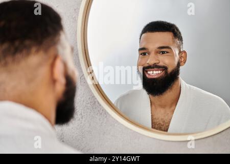 Ein lächelnder Mann bewundert sich im Spiegel, während er sich zu Hause entspannt. Stockfoto